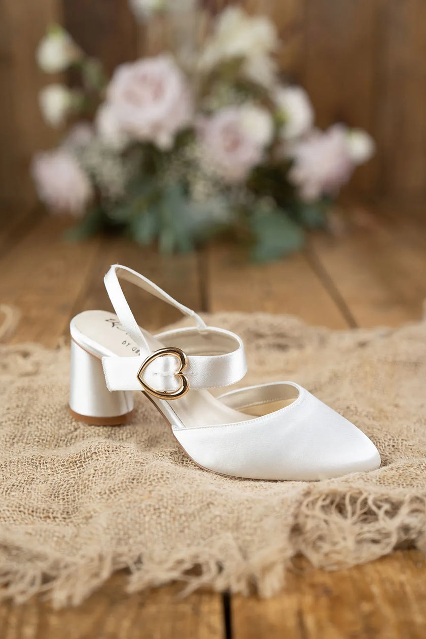 Zapatos de novia Amatista en color ivory con punta fina, hebilla de corazón dorada y tacón redondo de 5,5 cm, ideales para bodas y eventos elegantes.