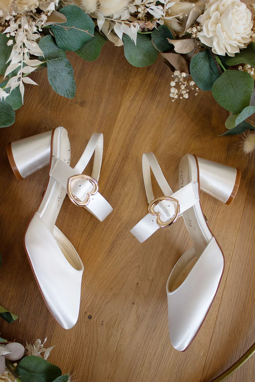 Zapatos de novia Amatista en color ivory con punta fina, hebilla de corazón dorada y tacón redondo de 5,5 cm, ideales para bodas y eventos elegantes.