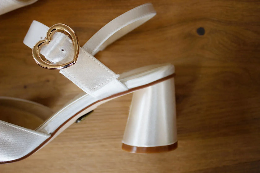 Zapatos de novia Amatista en color ivory con punta fina, hebilla de corazón dorada y tacón redondo de 5,5 cm, ideales para bodas y eventos elegantes.